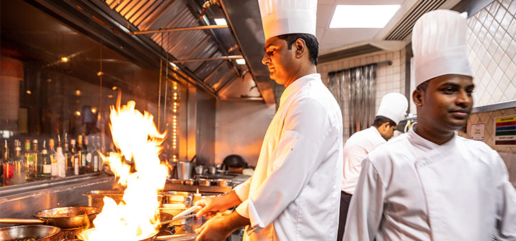 chef in busy kitchen cooking on open flame